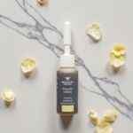 Φιαλίδιο Propolis Lösung 10ml σε μαρμάρινη επιφάνεια με κίτρινα πέταλα