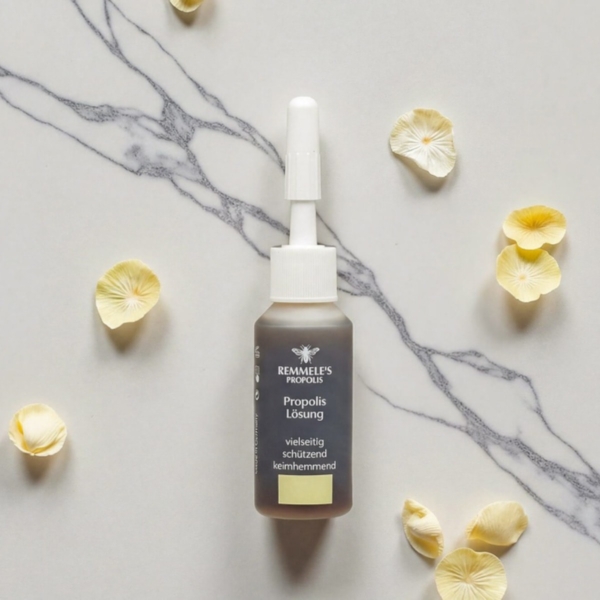Φιαλίδιο Propolis Lösung 10ml σε μαρμάρινη επιφάνεια με κίτρινα πέταλα