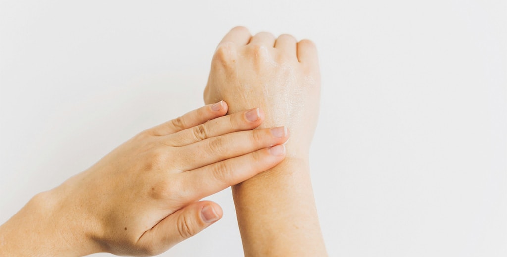Χέρια που απλώνουν κρέμα ενυδάτωσης στην επιδερμίδα